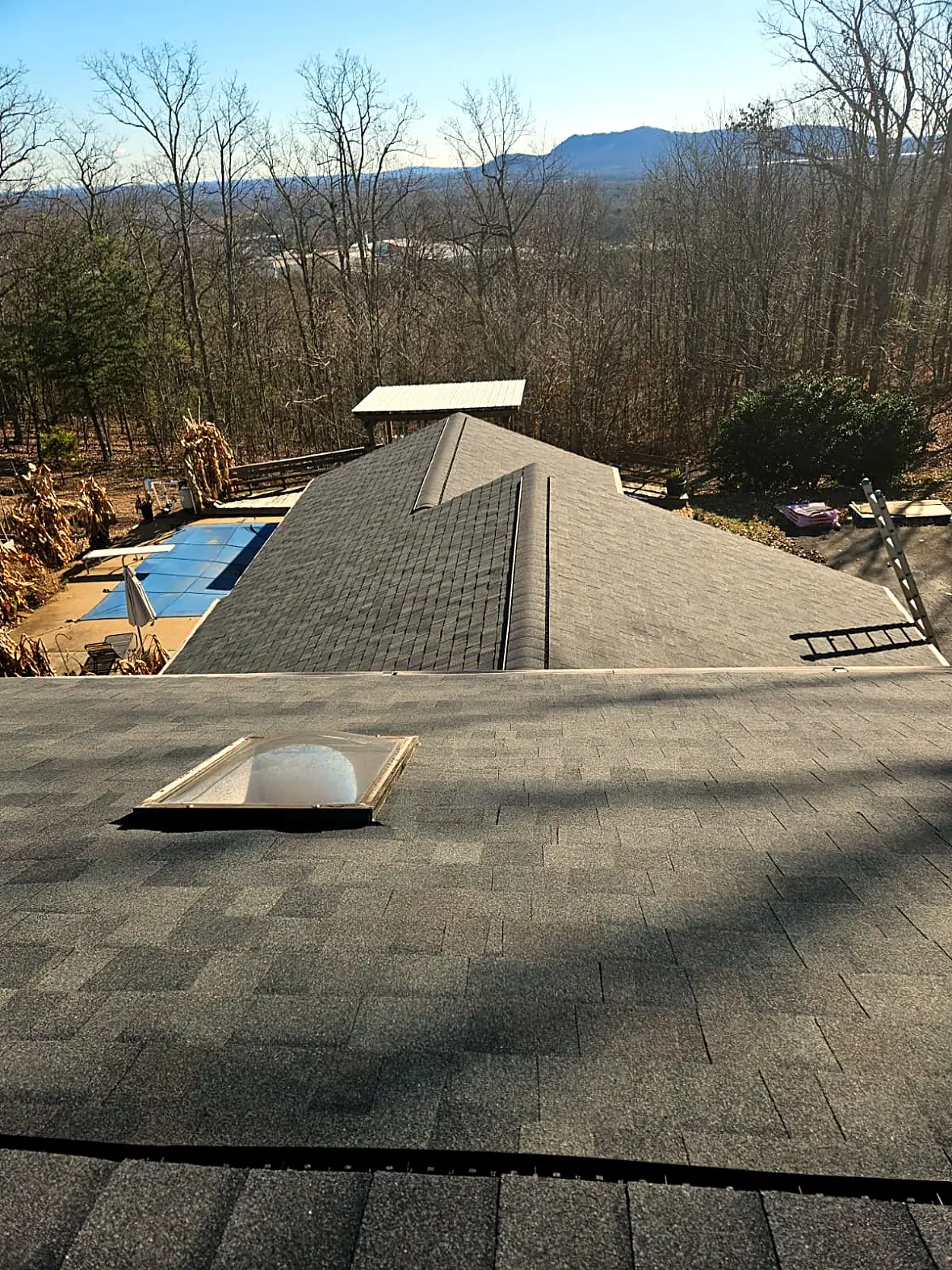 Finished gray shingle roof with a skylight, a pool and a mountain ridge in the distance, Kings Mountain NC