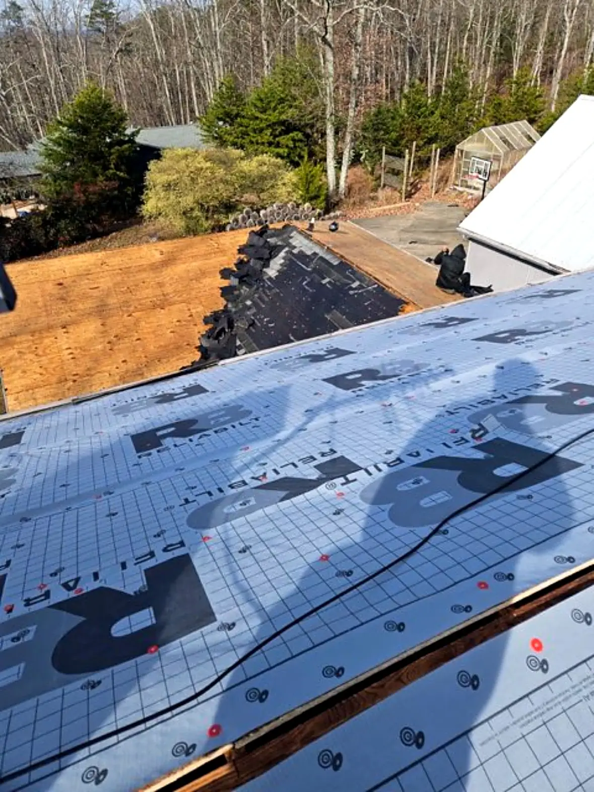 Bare roof decking next to new synthetic underlayment, with old shingles still on one section, Kings Mountain NC